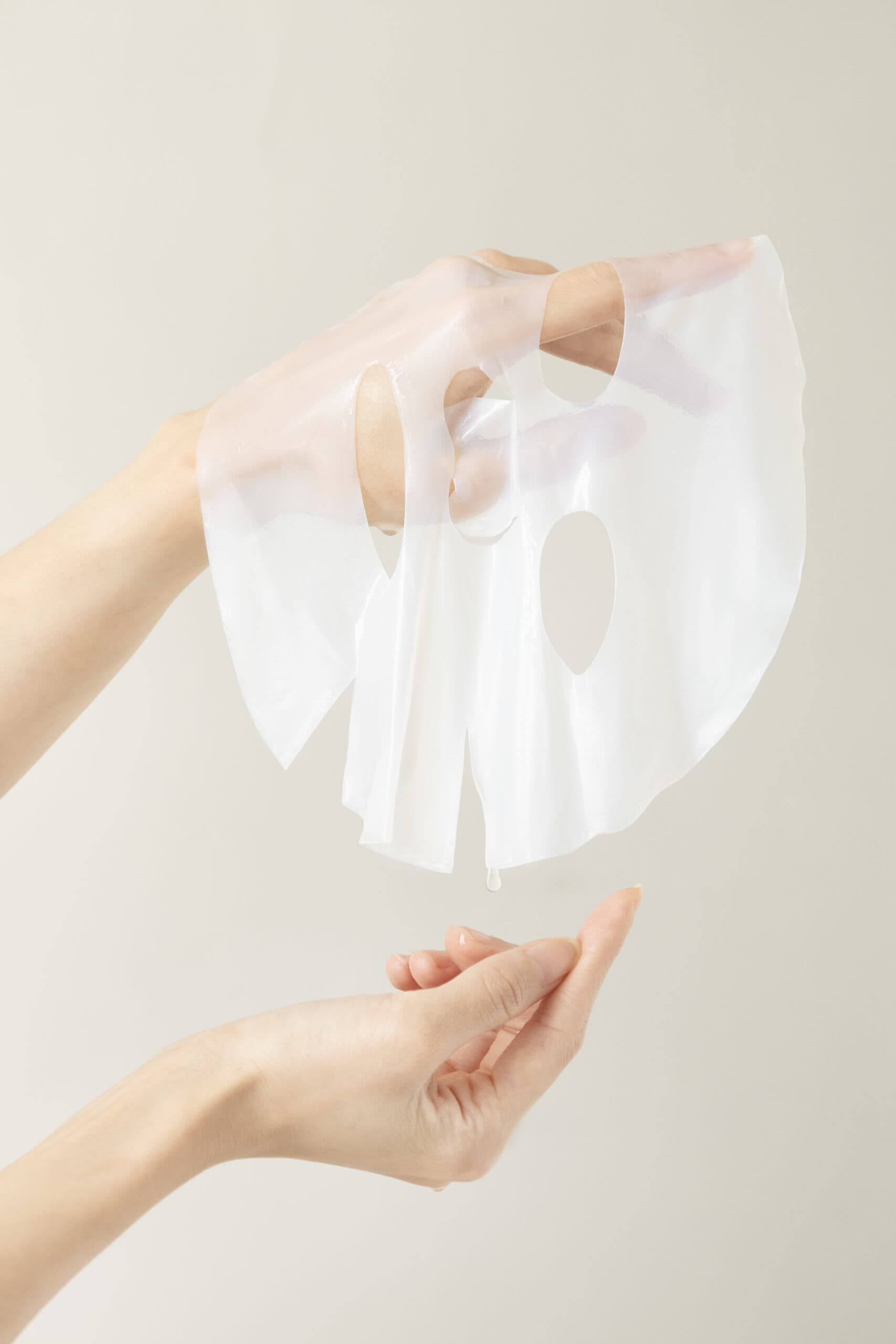 Facial sheet mask held by hands for e-commerce product photography.